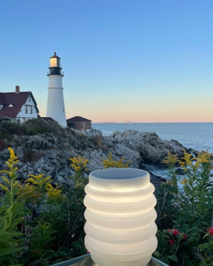 Lighthouse in Portland, Maine with a scenic ocean view, featuring a HAVEN solar portable lantern in the foreground.