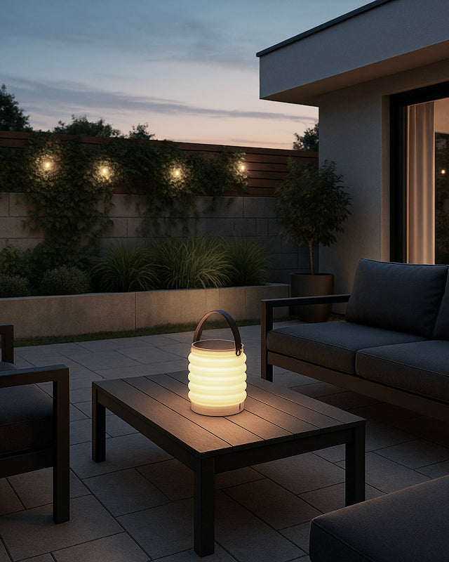 Modern outdoor patio deck with HAVEN solar portable lantern on a table and string lights illuminating the backyard at dusk.