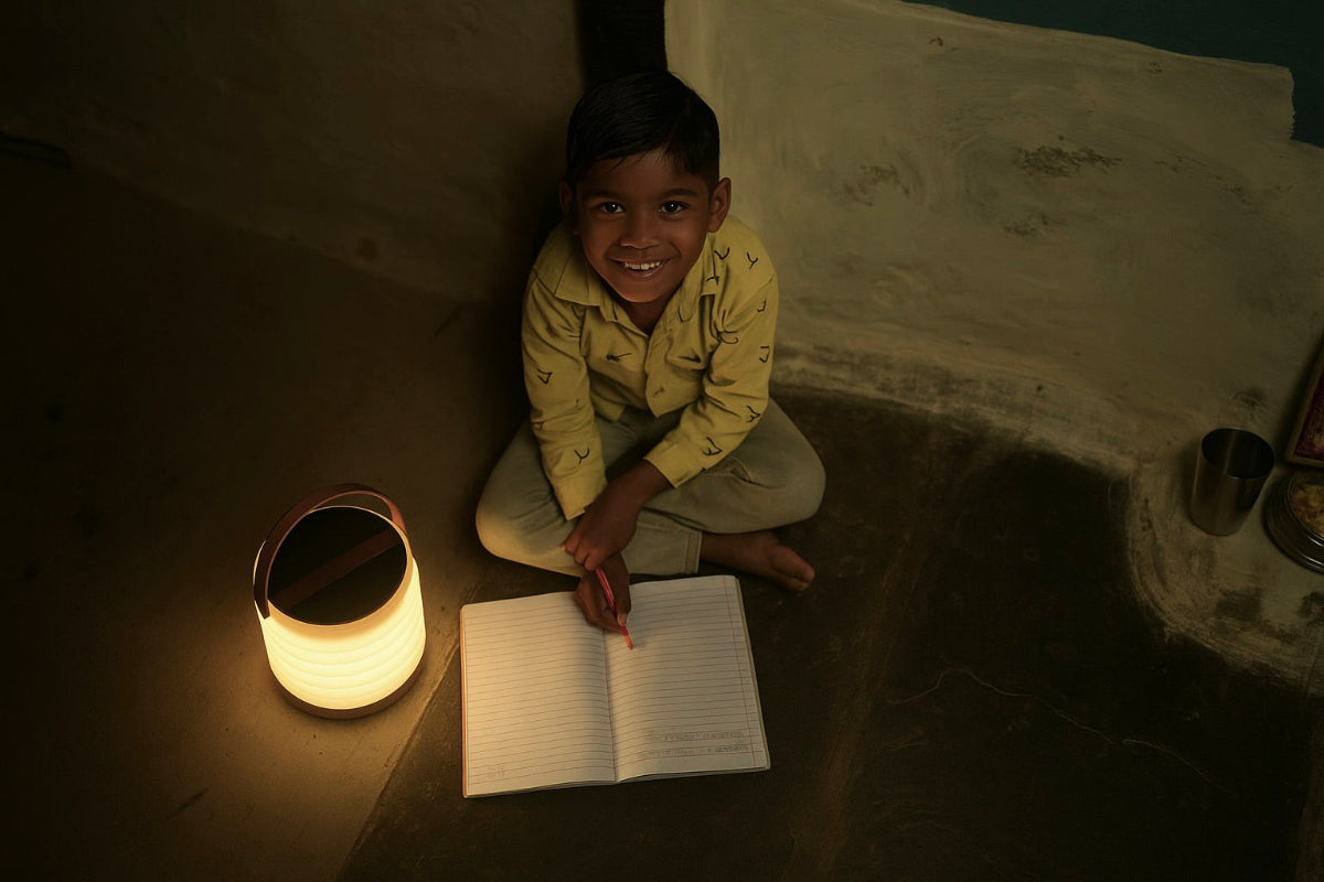 Child sitting on the floor with a book and an illuminated HAVEN solar portable lantern in a dimly lit room.