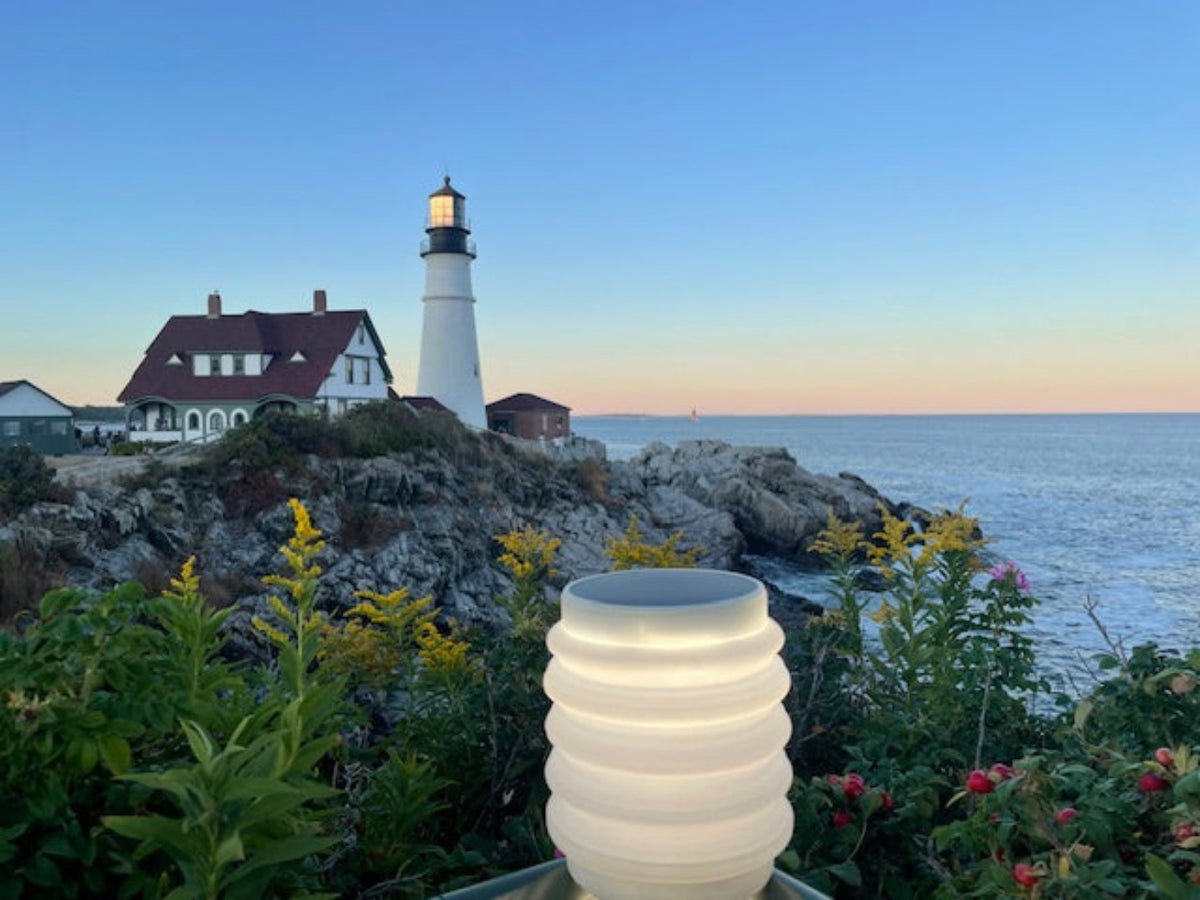 Lighthouse in Portland, Maine with a scenic ocean view, featuring a HAVEN solar portable lantern in the foreground.