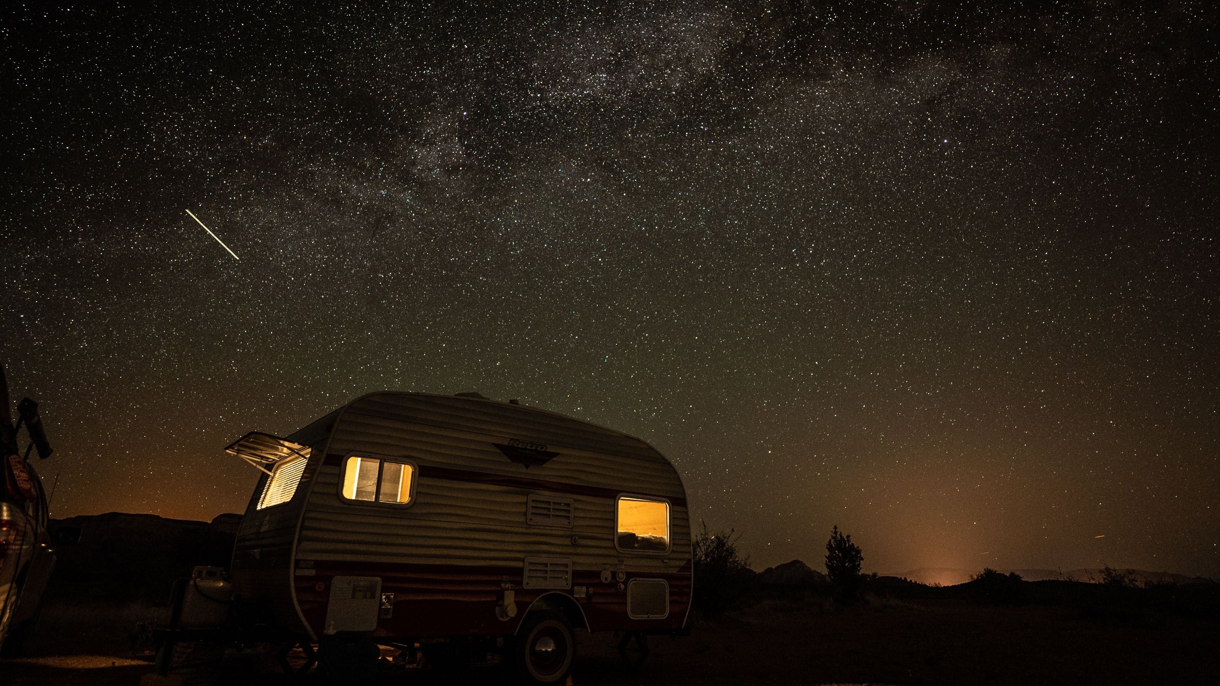 Vintage camper under a starry night sky with the Milky Way illuminated with a HAVEN Lantern.