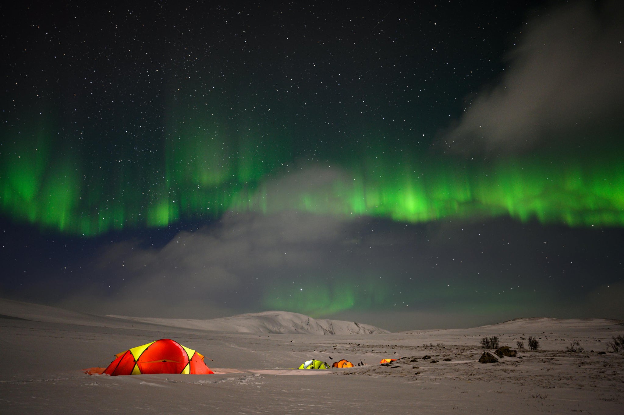 Tents illuminated with HAVEN Lanterns under the Northern Lights in a snowy landscape