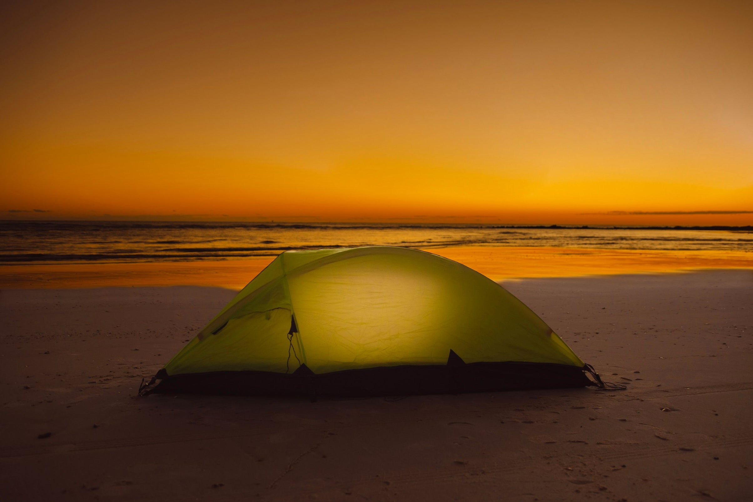 Tent illuminated with HAVEN Lantern on beach at sunset.