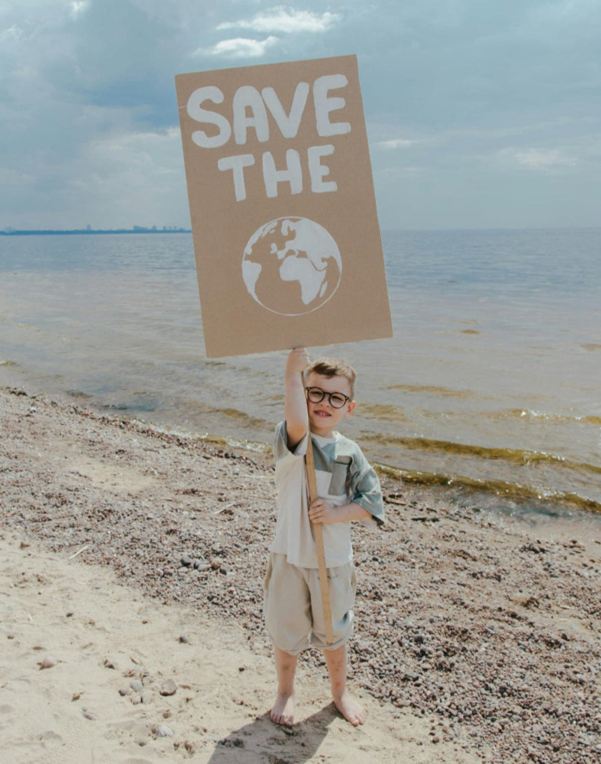 Child holding a sign saying to save the planet shows an interest in sustainability for future generations and the ability of corporations to engage through cause marketing.