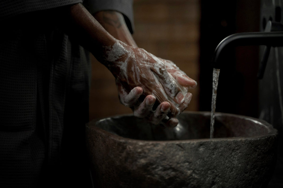 Person washing hands in a refugee setting lit up by a HAVEN solar portable lantern.
